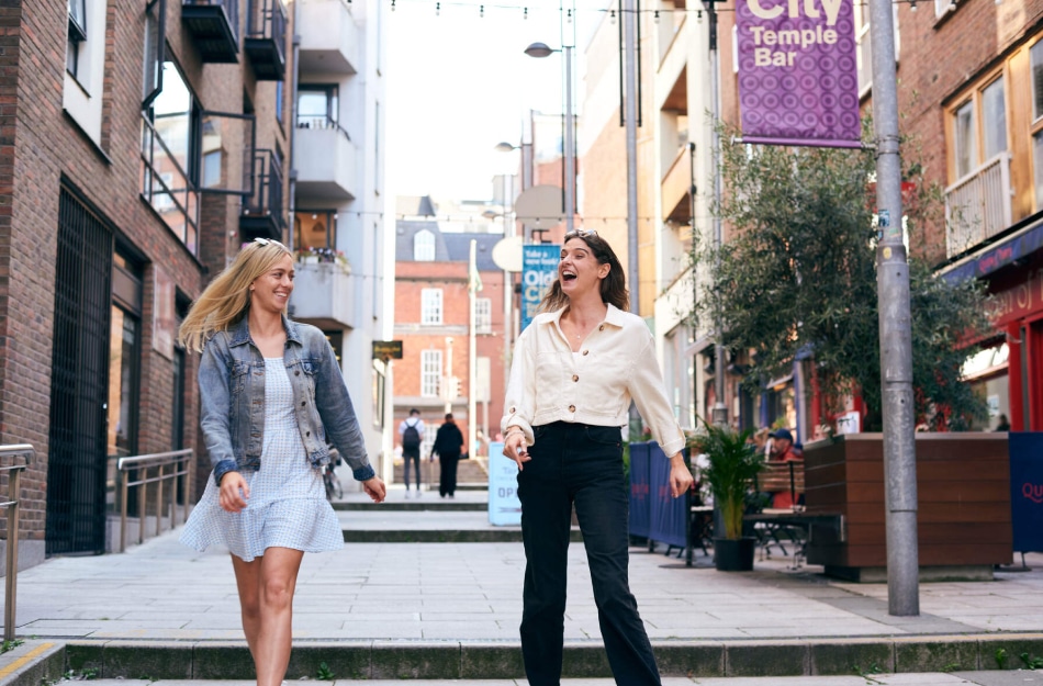 Two people smiling while walking through Cow's Lane in Dublin.