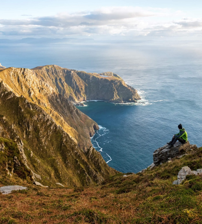 Aerial view of a person sitting on the Slieve League Cliffs, County Donegal.